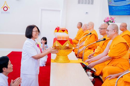 หญิงสวมชุดขาวประเคนพานพุ่มผ้าป่าแด่พระภิกษุสงฆ์ในพิธีทางศาสนา