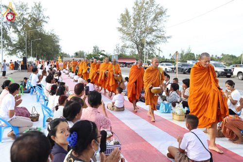 พระสงฆ์เดินรับบิณฑบาตจากประชาชนที่นั่งรอใส่บาตรริมชายหาด