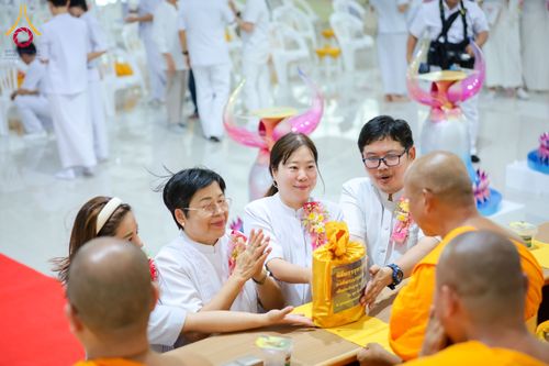 พุทธศาสนิกชนชุดขาวกำลังถวายผ้าป่าแด่พระภิกษุสงฆ์ในพิธีทางศาสนา