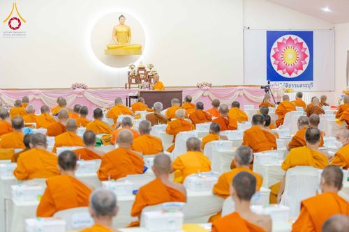 พระภิกษุสงฆ์จำนวนมากนั่งฟังการบรรยายภายในห้องประชุมที่มีพระอาจารย์เป็นผู้บรรยายบนเวที