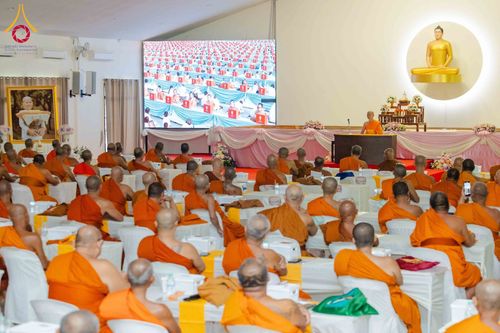 พระภิกษุสงฆ์นั่งฟังการบรรยายในห้องประชุมสัมมนา โดยมีพระภิกษุบรรยายบนเวทีและจอภาพขนาดใหญ่แสดงกิจกรรมโครงการกฐินสามัคคี