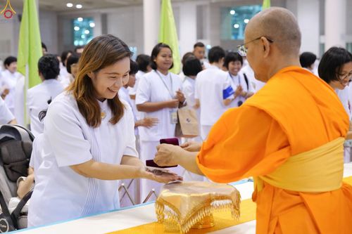 พระภิกษุสงฆ์มอบพระของขวัญให้หญิงสาวชุดขาวในพิธีการ