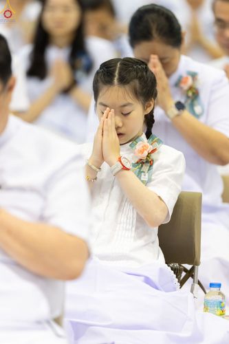 เด็กหญิงสวมชุดสีขาวกำลังพนมมือไหว้ด้วยความสงบในพิธีทางศาสนา