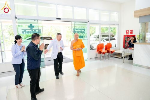 พระภิกษุสงฆ์เดินเข้าสู่อาคารศูนย์การแพทย์บุญรักษาโดยมีเจ้าหน้าที่ยืนต้อนรับ