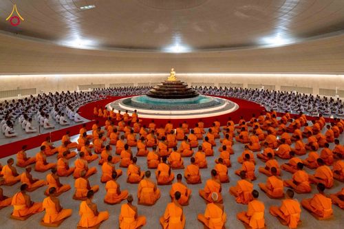 พระภิกษุสงฆ์และนักเรียนนายสิบตำรวจนั่งสมาธิพร้อมกันภายในห้องโถงขนาดใหญ่ที่มีพระพุทธรูปอยู่ตรงกลาง