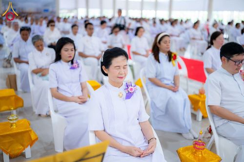 กลุ่มพุทธศาสนิกชนในชุดสีขาวนั่งสมาธิร่วมพิธีทางศาสนาภายในอาคาร
