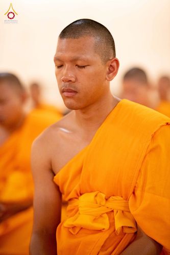 พระภิกษุสงฆ์ห่มจีวรสีส้มกำลังหลับตาทำสมาธิอย่างสงบ