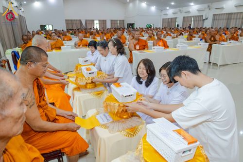 กลุ่มคนชุดขาวกำลังถวายของแด่พระภิกษุสงฆ์ในงานสัมมนาที่มีผู้เข้าร่วมจำนวนมาก