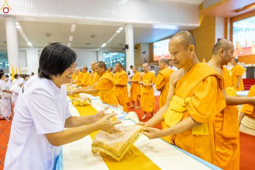 พระภิกษุสงฆ์กำลังส่งมอบพระของขวัญให้แก่พุทธศาสนิกชนในพิธี