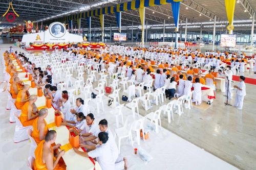 พุทธศาสนิกชนและพระภิกษุสามเณรจำนวนมากกำลังร่วมพิธีทางศาสนาภายในอาคารขนาดใหญ่