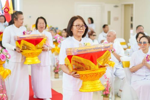 กลุ่มคนสวมชุดสีขาวถือพานพุ่มทองคำในพิธีทางศาสนาพุทธ