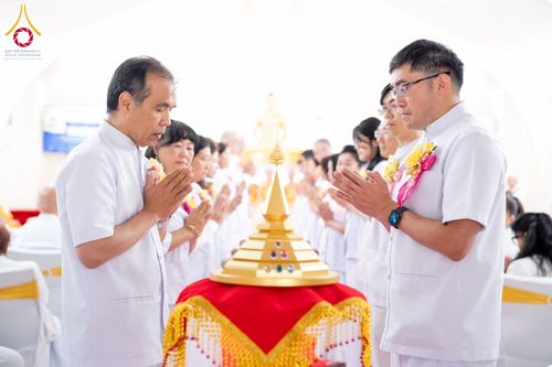 กลุ่มคนสวมชุดขาวพนมมือไหว้พระบรมสารีริกธาตุที่วางอยู่บนพานทองในพิธีทางศาสนา