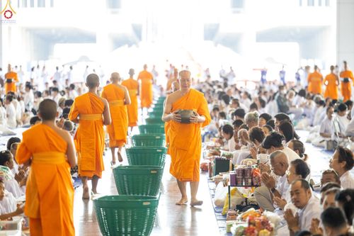 พระภิกษุสงฆ์เดินรับบิณฑบาตจากพุทธศาสนิกชนจำนวนมากภายในอาคาร