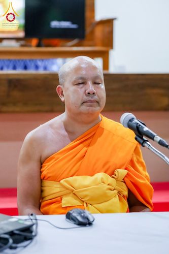 พระภิกษุสงฆ์กำลังนั่งหลับตาทำสมาธิโดยมีไมโครโฟนตั้งอยู่ด้านหน้า