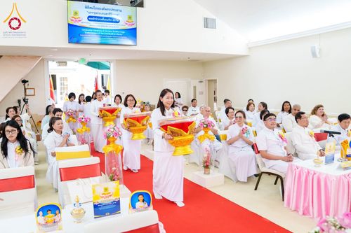 สาธุชนในชุดขาวถือพานพุ่มเดินบนพรมแดงในพิธีทอดผ้าป่า ณ วัดพระธรรมกายซิลิคอนวัลเลย์