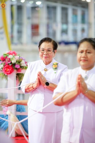 หญิงสูงวัยสวมชุดขาวพนมมือด้วยความสงบในพิธีการ