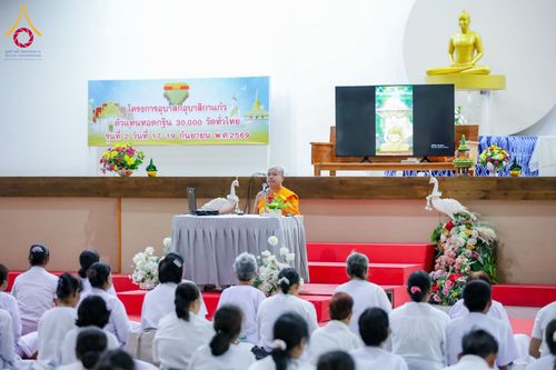 พระภิกษุสงฆ์นั่งบรรยายธรรมบนเวทีต่อหน้าผู้เข้าร่วมโครงการที่สวมชุดขาวจำนวนมาก