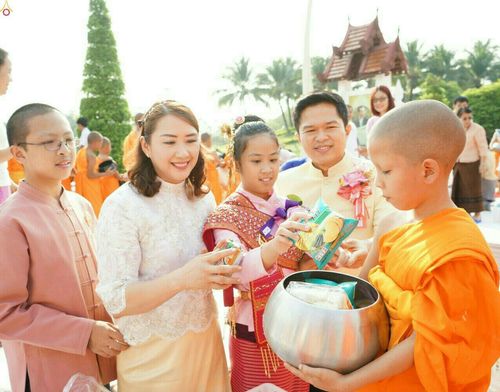 กลุ่มพุทธศาสนิกชนแต่งกายชุดพื้นเมืองกำลังใส่บาตรอาหารแห้งให้แก่สามเณรในพิธีตักบาตรที่จังหวัดเชียงใหม่