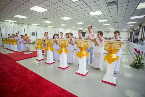 กลุ่มพุทธศาสนิกชนในชุดขาวร่วมพิธีทอดกฐินยืนเรียงแถวหน้าพานพุ่มทอง