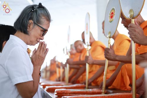หญิงสูงวัยสวมชุดขาวประนมมือไหว้พระสงฆ์ที่กำลังถือตาลปัตรประกอบพิธีบุพเปตพลี