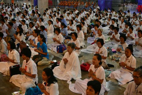 พุทธศาสนิกชนจำนวนมากสวมชุดสีขาวนั่งพนมมือสวดมนต์ในโครงการสวดธัมมจักกัปปวัตตนสูตร ๔ ล้านจบ