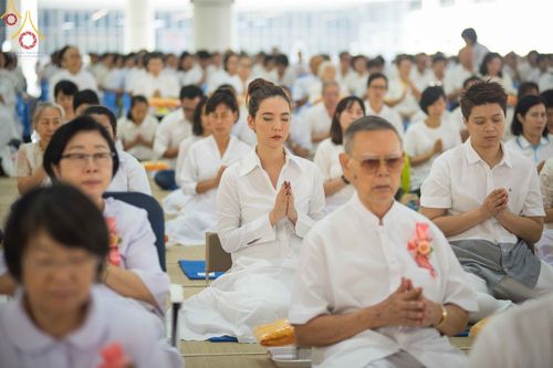 พุทธศาสนิกชนสวมชุดขาวนั่งพนมมือประกอบพิธีปุพพเปตพลีภายในหอฉันคุณยายอาจารย์ฯ วัดพระธรรมกาย