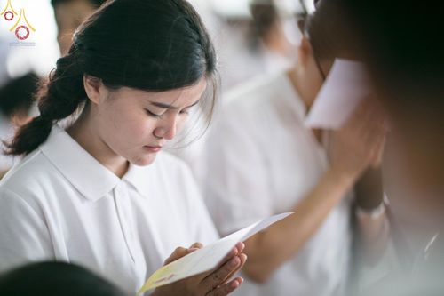 หญิงสาวสวมชุดขาวกำลังอ่านบทสวดมนต์ด้วยความตั้งใจในพิธีทางศาสนา