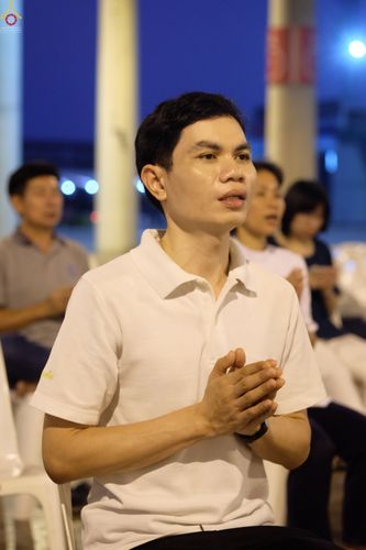 ชายหนุ่มสวมเสื้อสีขาวพนมมือสวดมนต์ในพิธีบูชามหาธรรมกายเจดีย์