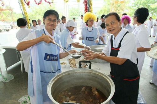 อาสาสมัครหญิงสองคนกำลังตักอาหารจากหม้อใบใหญ่เพื่อเตรียมเลี้ยงผู้มาร่วมงานบุญวันอาทิตย์ต้นเดือน