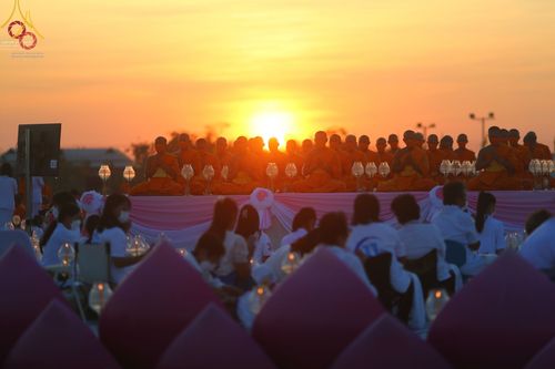 คณะสงฆ์และสาธุชนนั่งสมาธิและจุดประทีปในพิธีถวายเป็นพุทธบูชา ณ อนุสรณ์สถานบางปลา ยามพระอาทิตย์ตกดิน