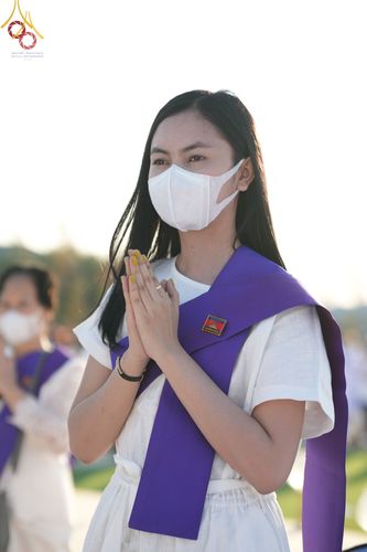 หญิงสาวสวมชุดขาวพนมมือในพิธีจุดประทีปถวายเป็นพุทธบูชาและบูชาธรรมมหาปูชนียาจารย์