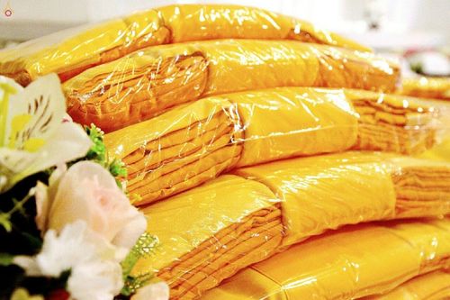 ชุดผ้าไตรจีวรสีเหลืองทองห่อพลาสติกวางซ้อนกันเพื่อเตรียมใช้ในงานบุญกฐิน