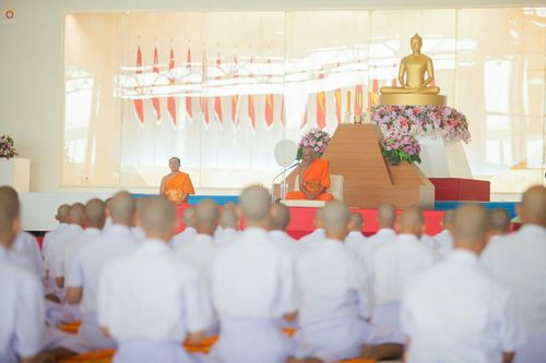 กลุ่มผู้เข้าร่วมพิธีบรรพชาธรรมทายาทรุ่นอุดมศึกษาปี ๒๕๕๙ นั่งสมาธิพร้อมเพรียงกันภายในอาคารที่มีพระพุทธรูปประดิษฐานอยู่ด้านหน้า