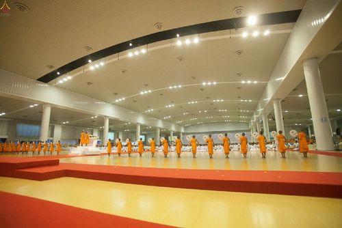พระภิกษุสงฆ์ยืนเรียงแถวหน้ากระดานภายในอาคารโถงกว้างในพิธีวันสมาธิโลก
