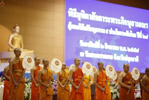 พระภิกษุและสามเณรยืนถือพัดยศในพิธีมุทิตาสักการะผู้สอบได้เปรียญธรรม ๙ ประโยค