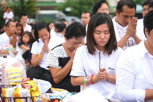 กลุ่มพุทธศาสนิกชนสวมชุดสีขาวประนมมือด้วยความสงบในพิธีตักบาตรพระสงฆ์ 309 รูป ณ หมู่บ้านพฤกษา B