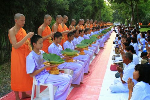พระสงฆ์ตัดปอยผมให้เยาวชนชายในชุดสีขาวเพื่อเตรียมบรรพชาสามเณร โดยมีญาติโยมนั่งพนมมืออยู่ด้านข้าง