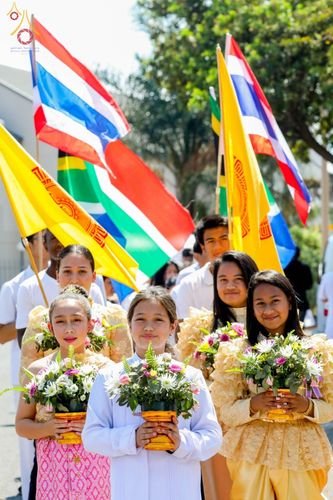 กลุ่มเยาวชนหญิงถือพานดอกไม้ร่วมขบวนแห่ในพิธีฉลองอุโบสถและทอดกฐินที่วัดพระธรรมกายโจฮันเนสเบิร์ก