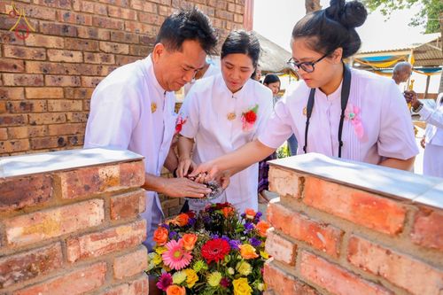 กลุ่มพุทธศาสนิกชนในชุดสีขาวกำลังประกอบพิธีโปรยดอกไม้ในงานฉลองอุโบสถและทอดกฐินที่แอฟริกาใต้