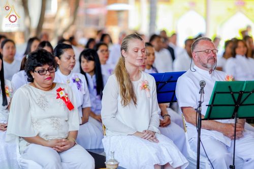 กลุ่มสาธุชนชายหญิงสวมชุดขาวนั่งหลับตาทำสมาธิในพิธีฉลองอุโบสถวัดพระธรรมกายโจฮันเนสเบิร์ก