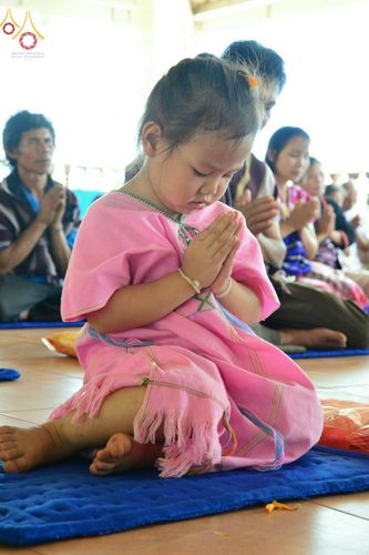 เด็กหญิงสวมชุดพื้นเมืองสีชมพูนั่งพนมมือไหว้พระในพิธีทอดกฐินสามัคคีที่วัดทุ่งเจริญธรรม