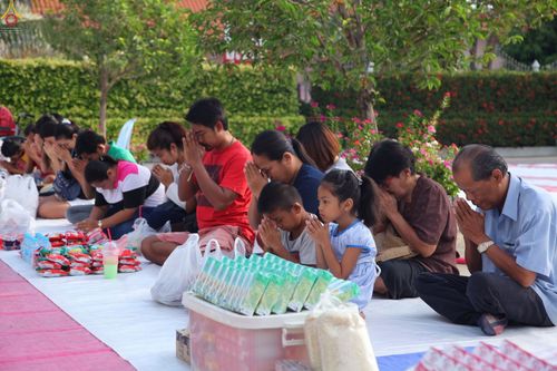 กลุ่มพุทธศาสนิกชนนั่งพนมมือเตรียมตักบาตรพระภิกษุสามเณรภายในวัดดอนใหญ่