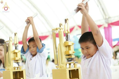 เด็กชายสวมชุดขาวกำลังใช้เครื่องมือกดพิมพ์พระของขวัญในพิธีพิมพ์พระรุ่นบรรลุธรรม
