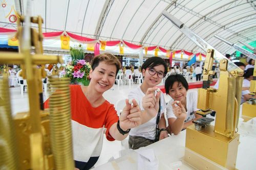 กลุ่มพุทธศาสนิกชนหญิงสามคนกำลังถือองค์พระขนาดเล็กที่พิมพ์เสร็จแล้วในพิธีพิมพ์พระของขวัญรุ่นบรรลุธรรม