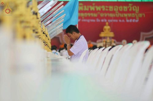 ชายสวมชุดขาวพนมมือในพิธีพิมพ์พระของขวัญรุ่นบรรลุธรรม