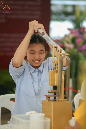 หญิงสาวกำลังใช้เครื่องกดพิมพ์พระของขวัญรุ่นบรรลุธรรมด้วยความตั้งใจ