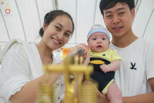 พ่อแม่และลูกน้อยกำลังร่วมกันประกอบพิธีพิมพ์พระของขวัญ รุ่นบรรลุธรรม