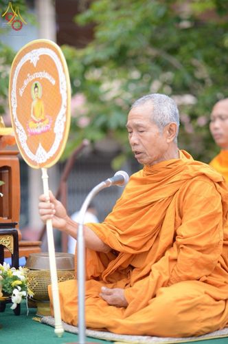 พระสงฆ์นั่งถือตาลปัตรประกอบพิธีทางศาสนาหน้าไมโครโฟน