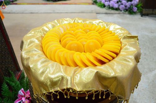 แผ่นเทียนสีเหลืองทรงกลมวางเรียงในพานรองด้วยผ้าสีทองสำหรับพิธีหล่อเทียนพรรษา