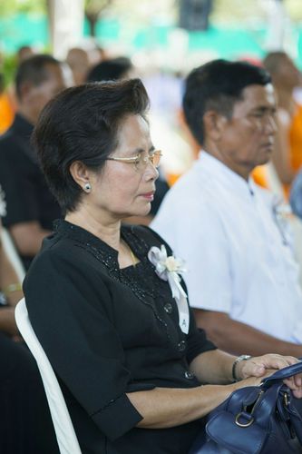 หญิงไทยสวมชุดไว้ทุกข์สีดำนั่งสำรวมในพิธีบำเพ็ญกุศลสวดพระอภิธรรมถวายพระบรมศพ